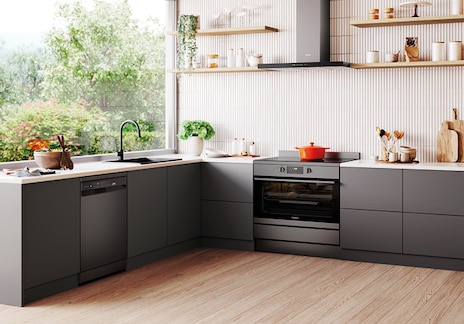 Contemporary kitchen with Westinghouse black appliances including oven, dishwasher, and fridge, featuring light gray cabinets, black faucet, and garden-facing windows.