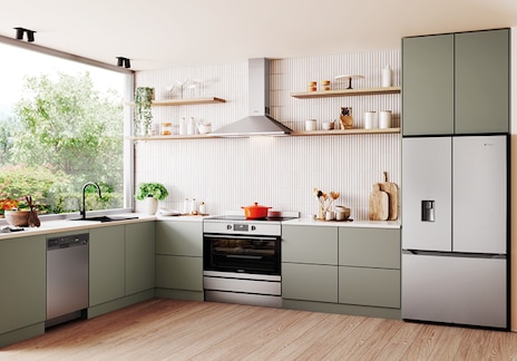 Australian kitchen with stainless steel appliances including a dishwasher, built-in oven, and French door fridge, featuring dark grey cabinets, white countertops, and garden-facing windows.